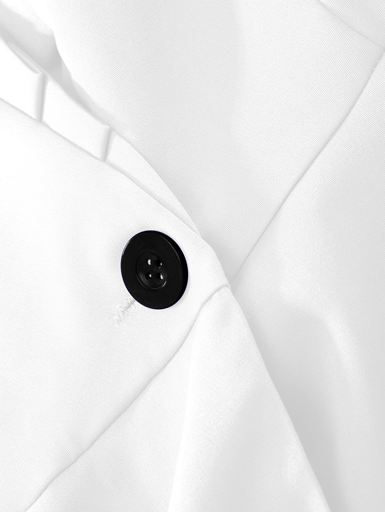 czarny guzik na białym materiale damskiej kurtki peleryny