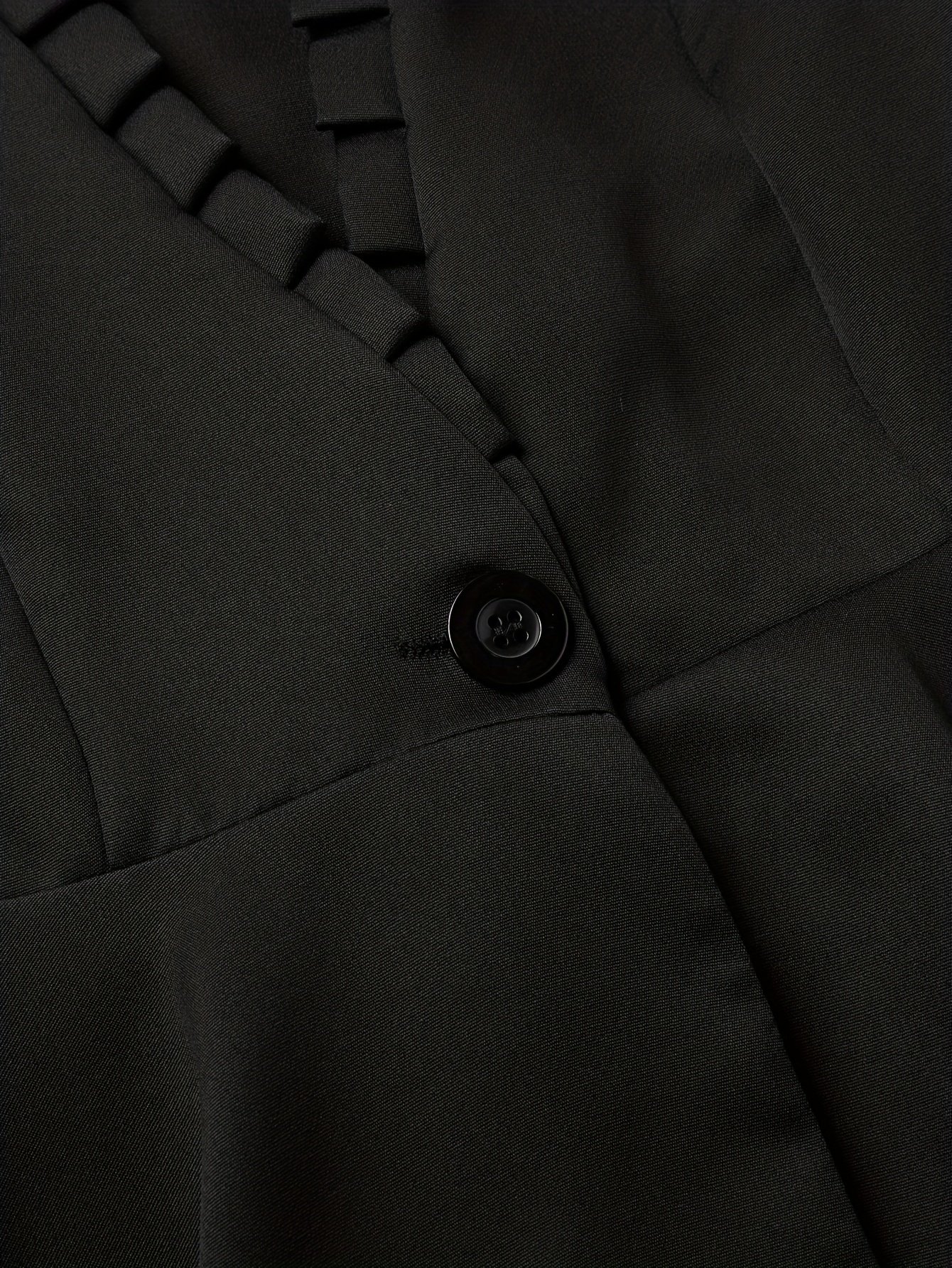 czarny guzik na czarnym materiale damskiej kurtki peleryny