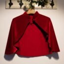 czerwona aksamitna peleryna damska zawieszona na wieszaku na białej ścianie