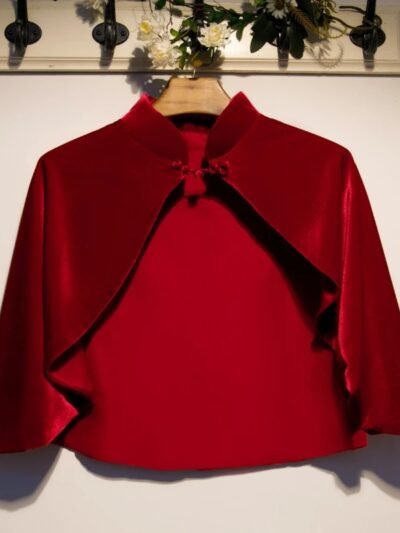 czerwona aksamitna peleryna damska zawieszona na wieszaku na białej ścianie