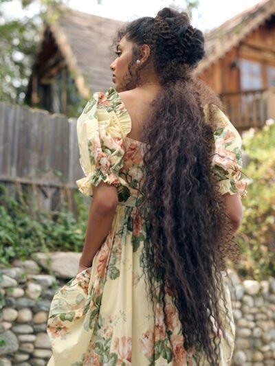 kobieta z długimi brązowymi włosami nosząca żółtą suknię balową midi obrócona tyłem