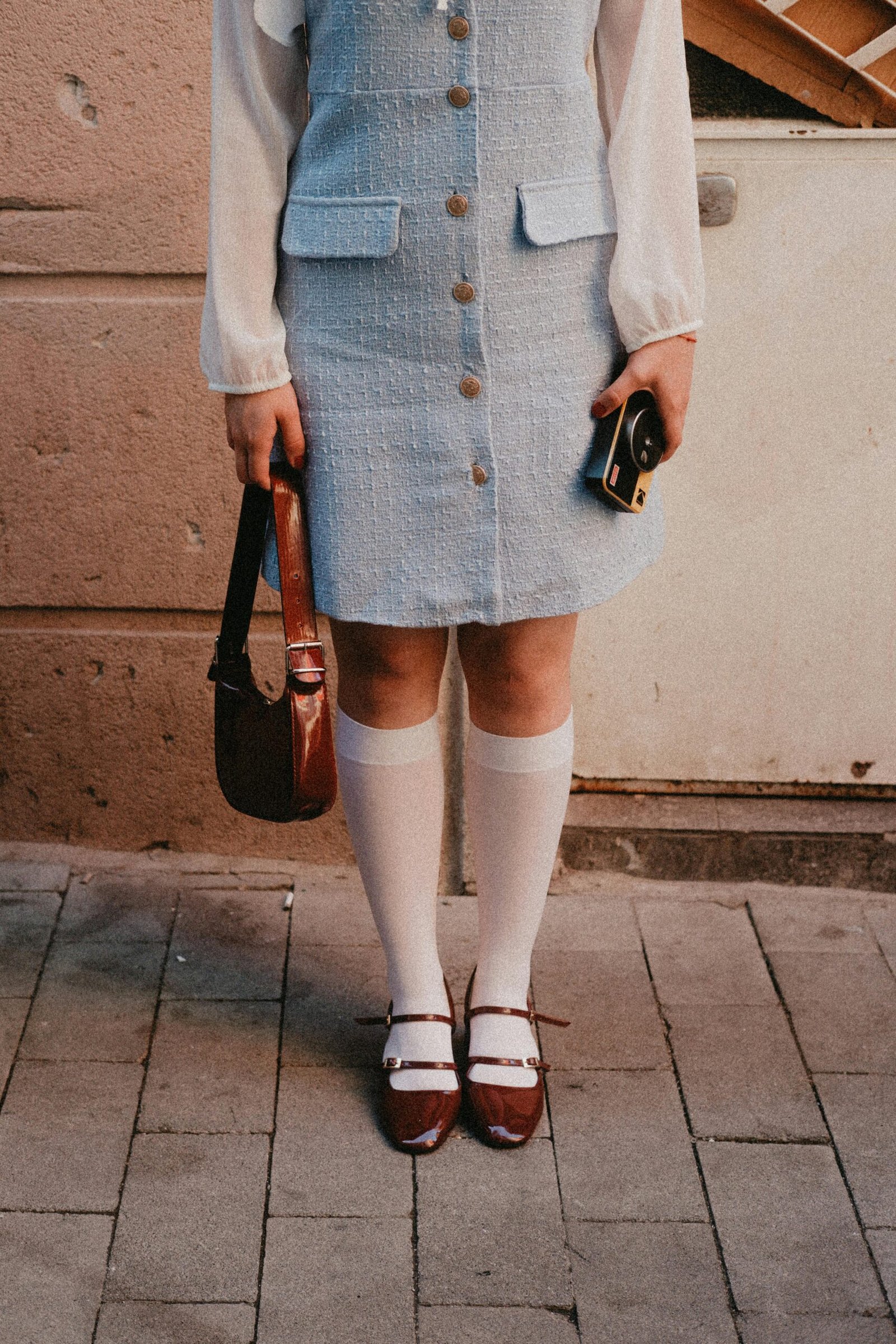 kobieta nosząca jasnoniebieską tweedową sukienkę, białe podkolanówki i bordowe buty retro