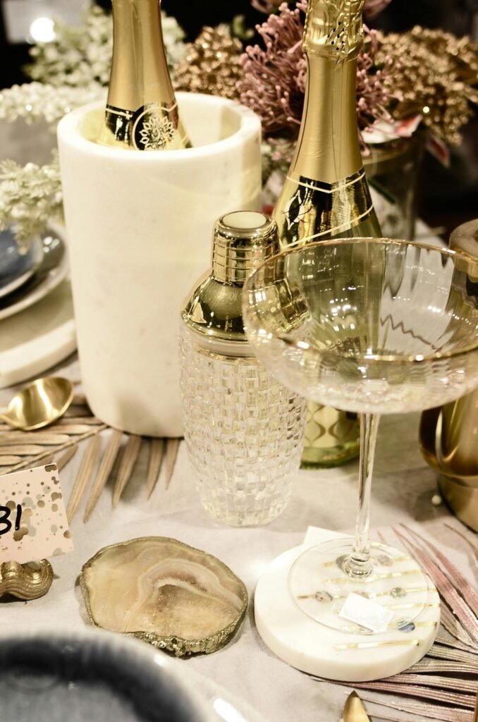 złoto-czarne dekoracje położone obok butelki szampana na stole jak reprezentacja tego, jak udekorować salę na bal karnawałowy